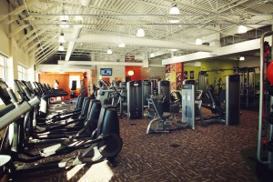 Inside and Anytime Fitness gym with cardio equipment on the left, and machines on the right