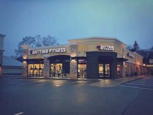 night time shoot of a yellow anytime fitness gym with machines visible through windows