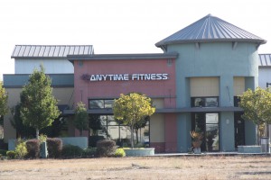Terracotta, blue, and yellow Anytime Fitness location with anytime fitness signage